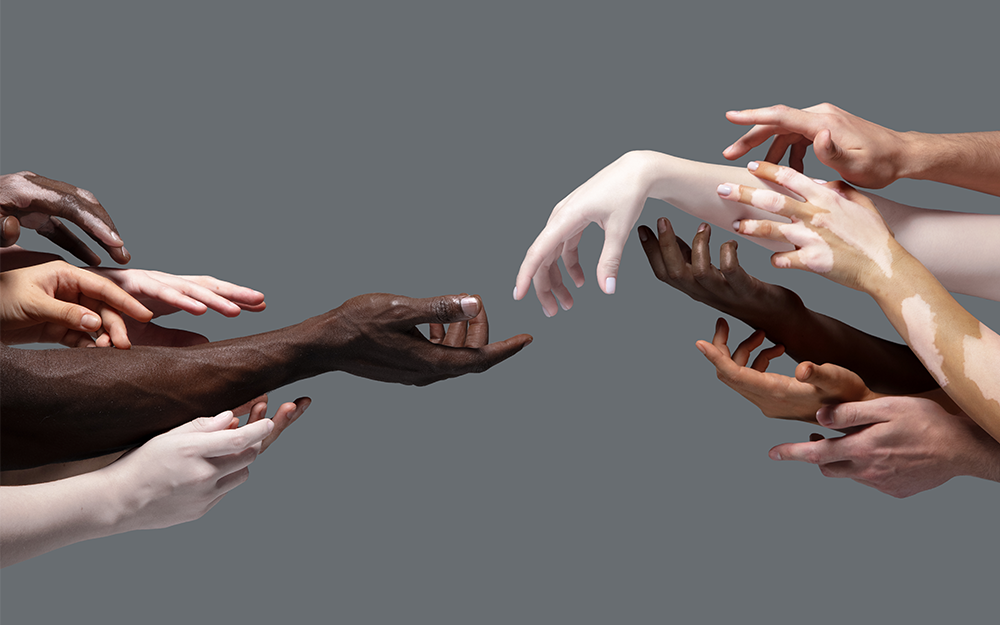 11 human hands with different skin tones in a grey background.